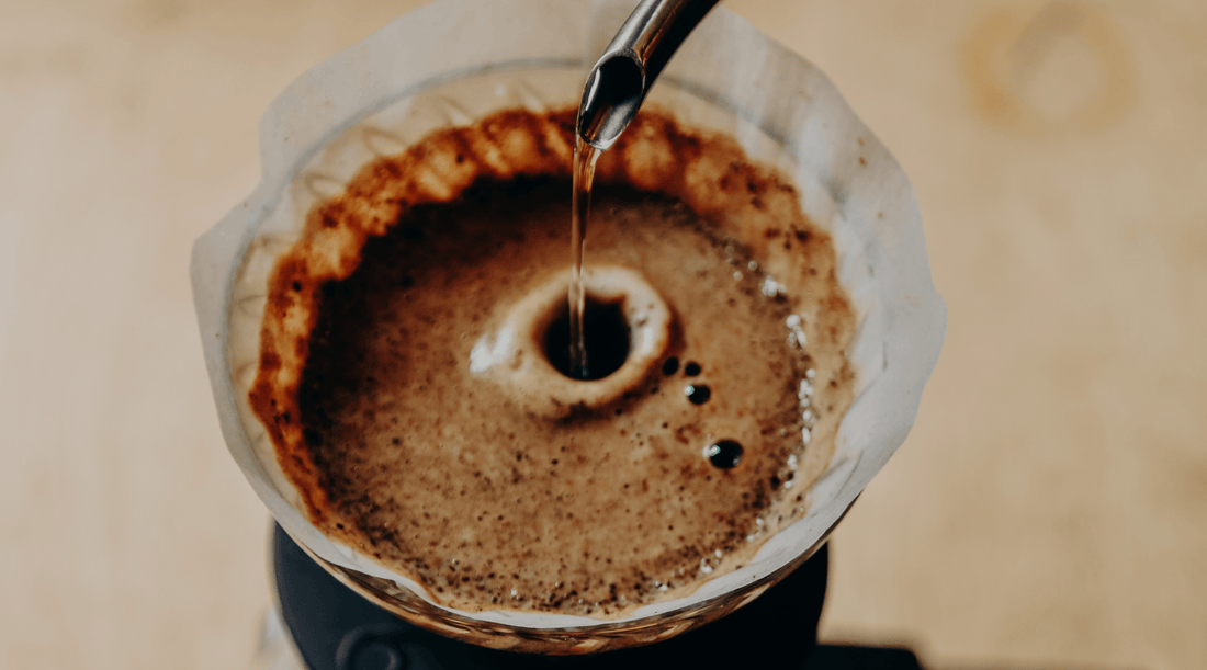 Pouring hot water over coffee grounds in a paper filter, showcasing the brewing process.